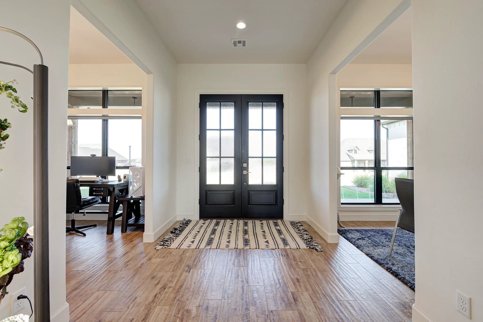 Foyer looking back toward the black glass front doors, flanked by a home office and a sitting area