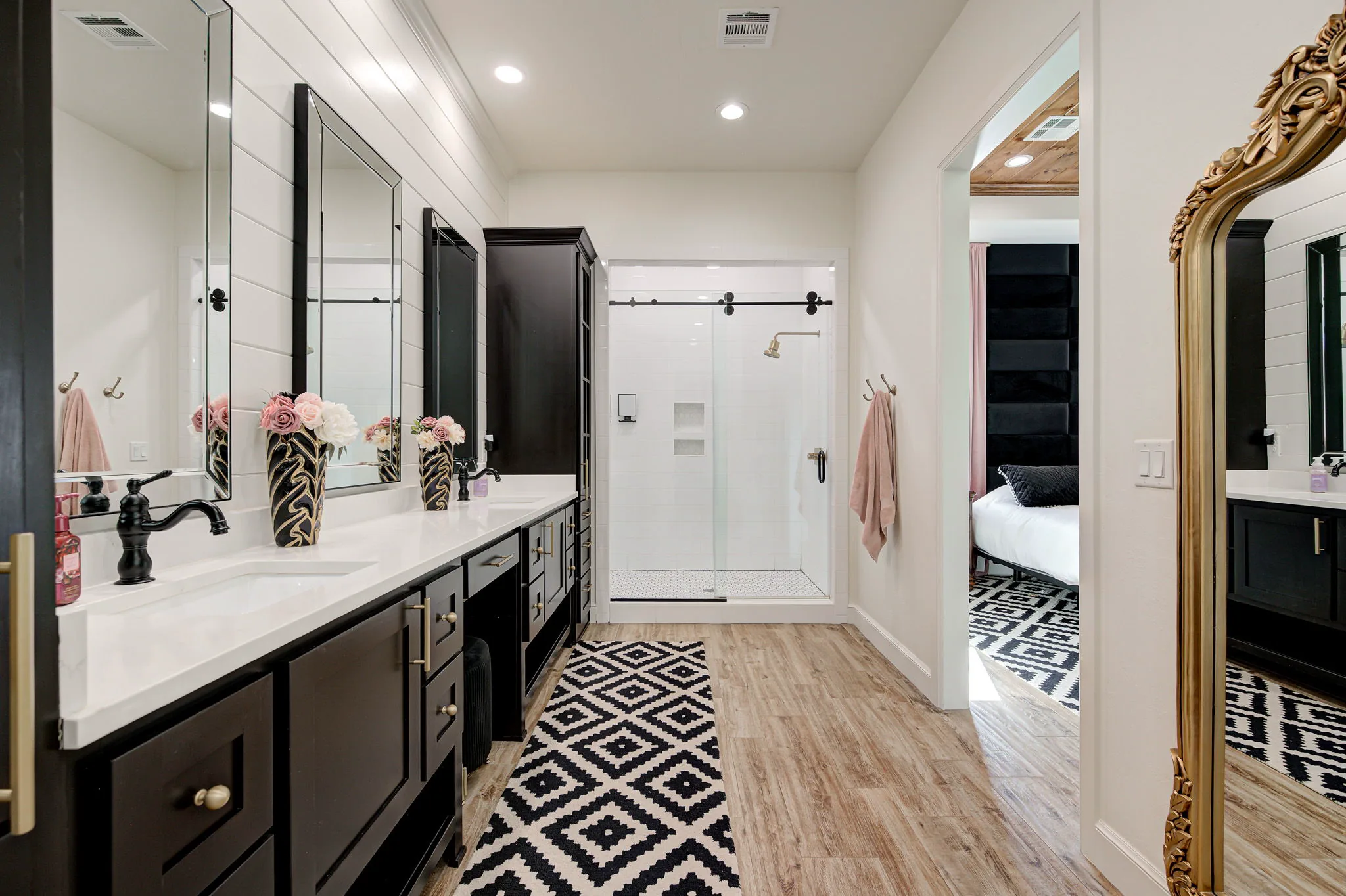 Primary ensuite with dual vanities and a glass walk-in shower, open to the primary bedroom
