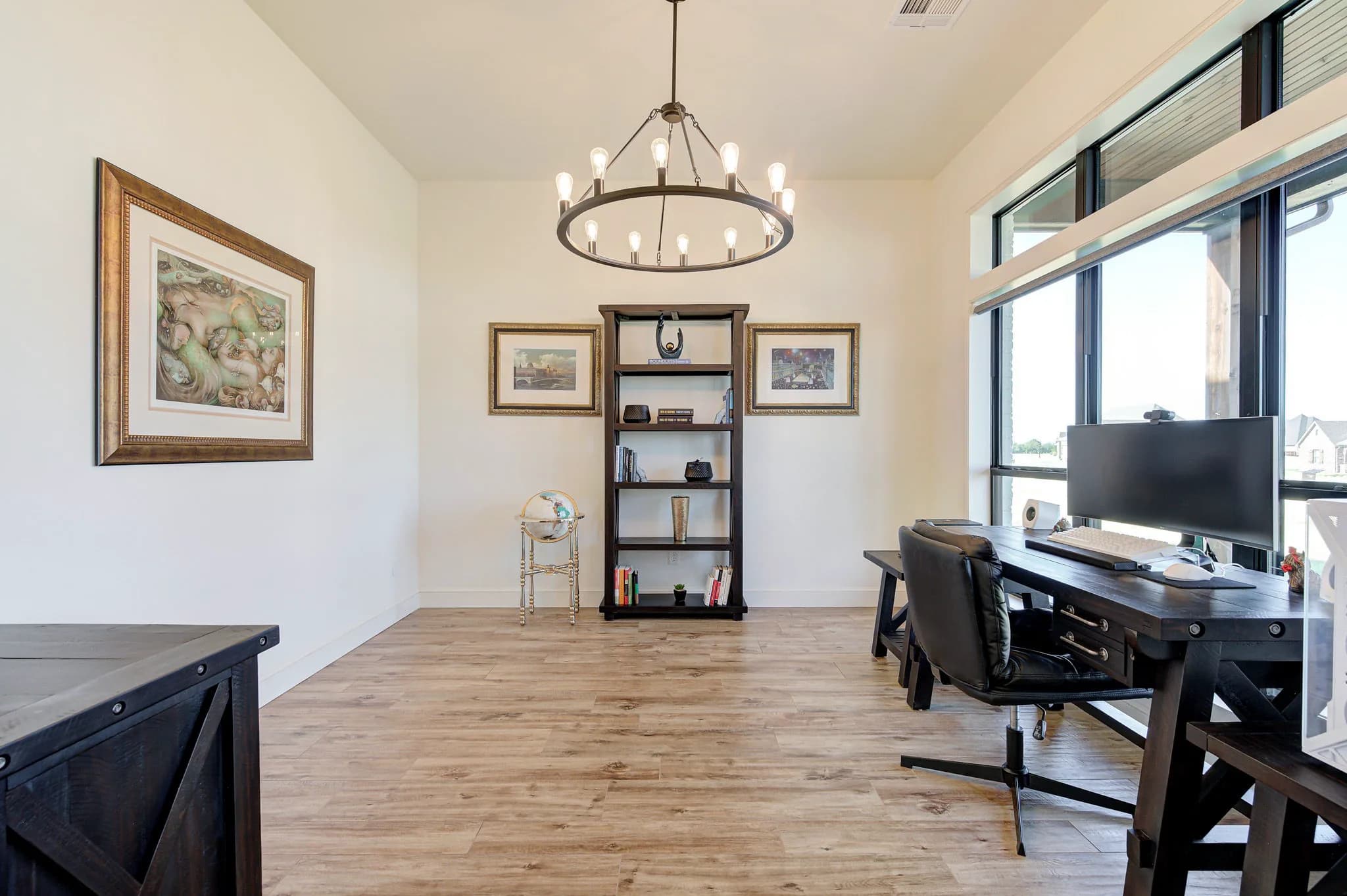 Home office with an iron ring chandelier, built-in shelving, and large windows