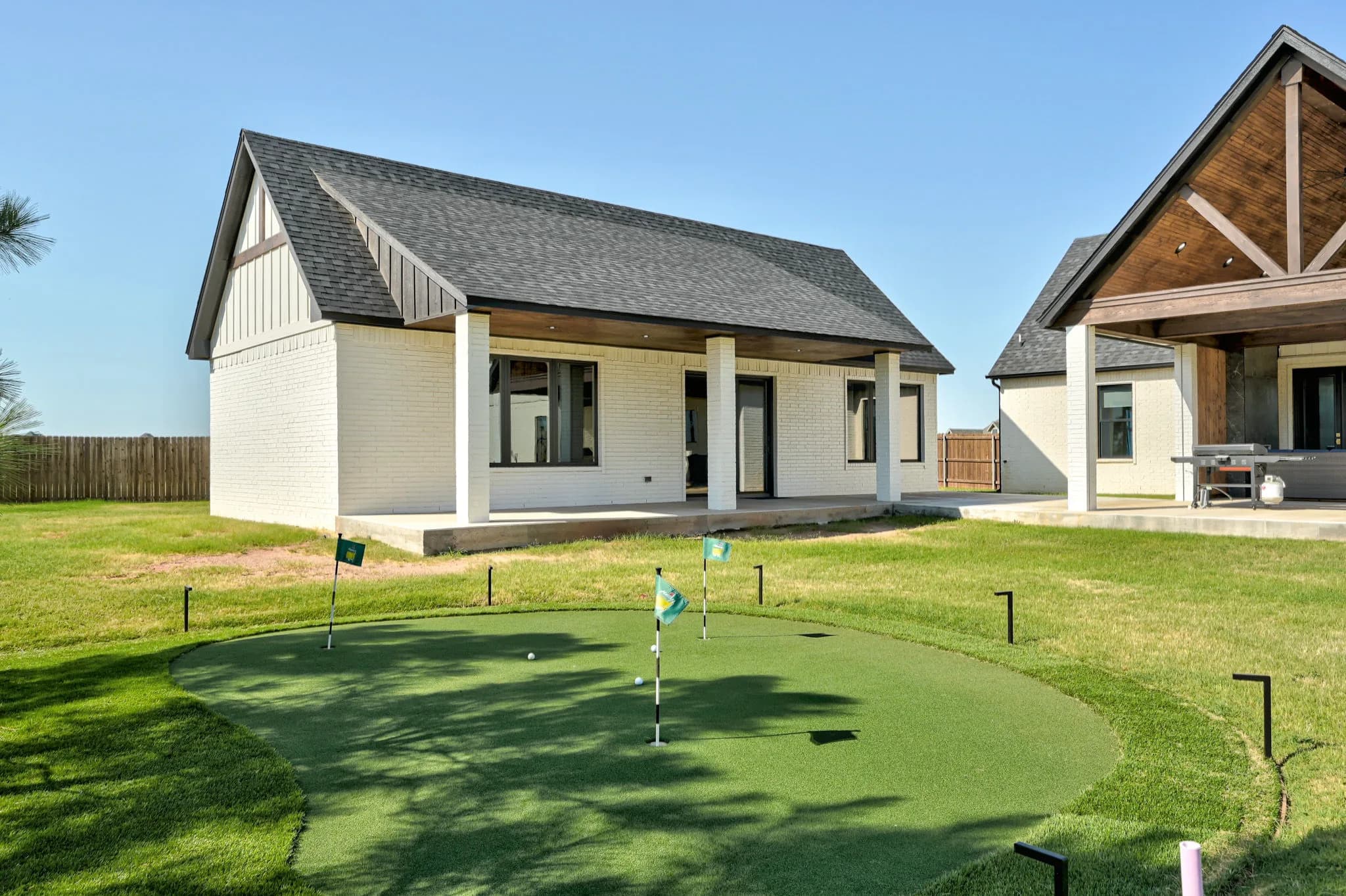 Detached guest and entertainment building with its own covered porch, set across the backyard from the main home
