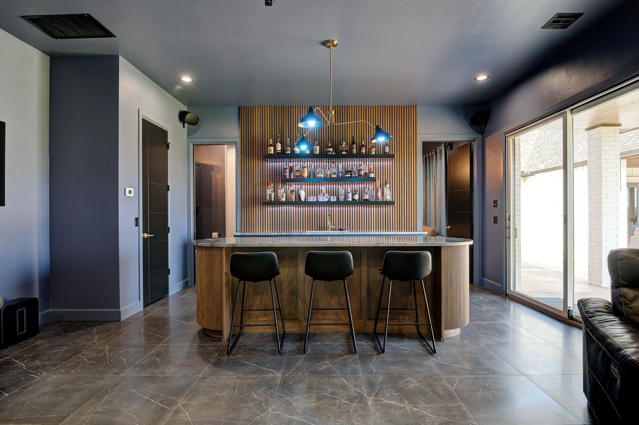 Custom wet bar with a backlit slat wall, floating shelves, a marble waterfall island, and counter seating