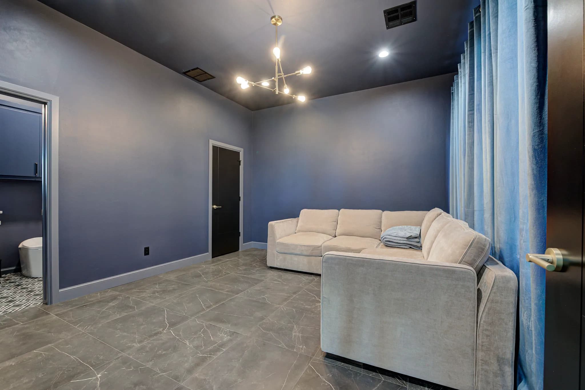 Flex lounge in the entertainment building with a sectional sofa, a statement chandelier, and an adjoining full bath